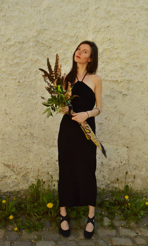 Model is wearing reversible black midi dress tied behind neck