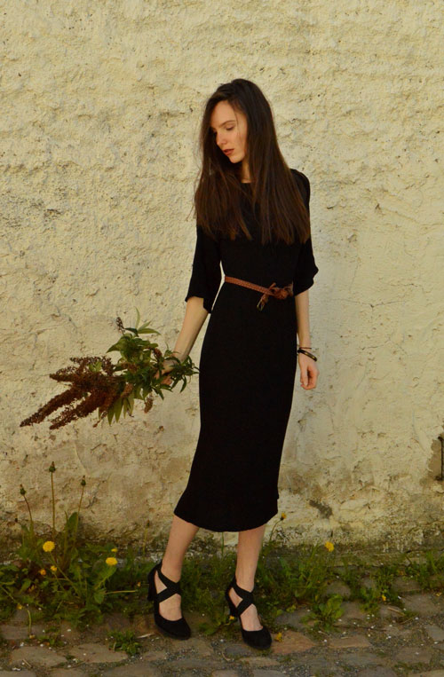 Model is wearing reversible black midi dress with two sleeves