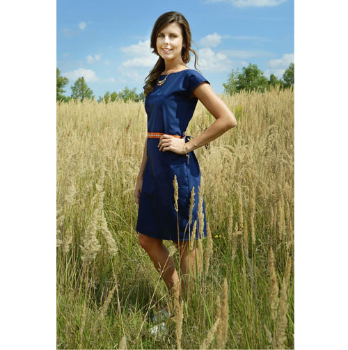 The model is wearing knee lenght blue dress with short sleeves and orange indian motive placed on the waistline