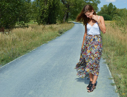 The model is wearing long flowery boho skirt which is shorter on the front side.