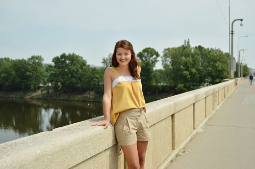 The woman is wearing loose yellow tom with white lace in the front.