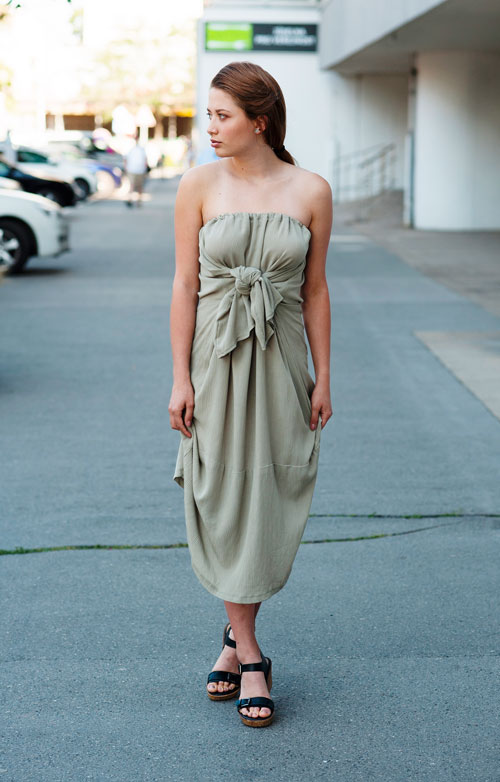 Model is wearing pale green midi strapless dress with bow in front