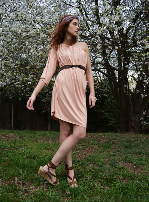 Model is wearing reversible salmon pink short dress with one sleeve