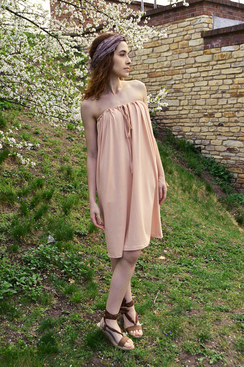 Model is wearing short salmon pink strapless variable dress